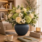گلدان شیشه‌ای دکوراتیو رومیزی مدل ژاکلین سایز 16 و 20؛ تلفیقی از ظرافت، سادگی و طراحی لوکس اگر به دنبال یک گلدان شیشه‌ای خاص با طراحی متفاوت و ظاهری چشم‌نواز برای تکمیل دکوراسیون منزل یا محل کار خود هستید، گلدان شیشه‌ای دکوراتیو رومیزی مدل ژاکلین سایز 16 و 20 می‌تواند انتخابی ایده‌آل باشد. این گلدان با فرم گرد و ظریف، خطوط برجسته عمودی روی بدنه، رنگ کرم مرواریدی و لبه طلایی براق، ترکیبی زیبا از سبک مدرن و کلاسیک را ارائه می‌دهد. طراحی ساده اما شیک این مدل باعث شده تا بدون ایجاد شلوغی، جلوه‌ای لوکس به فضای شما اضافه کند. مدل ژاکلین در دو سایز 16 سانتی‌متر و 20 سانتی‌متر عرضه شده است که امکان استفاده به‌صورت تکی یا ترکیبی را فراهم می‌کند. قرار دادن این دو سایز در کنار هم، یک چیدمان هماهنگ و حرفه‌ای ایجاد کرده و باعث جذاب‌تر شدن دکوراسیون می‌شود. طراحی خاص با خطوط برجسته و فرم چشم‌نواز یکی از ویژگی‌های برجسته گلدان شیشه‌ای دکوراتیو رومیزی مدل ژاکلین سایز 16 و 20، طراحی بدنه آن است. خطوط عمودی ظریف که از قسمت بالایی تا پایین گلدان امتداد دارند، باعث ایجاد بافتی زیبا و منظم شده‌اند. این شیارها هنگام برخورد نور، انعکاس‌های ملایمی ایجاد می‌کنند و باعث می‌شوند سطح گلدان درخشش خاصی داشته باشد. فرم گرد و متناسب این گلدان حس لطافت و آرامش را به محیط منتقل می‌کند. این طراحی باعث شده مدل ژاکلین هم برای فضاهای مینیمال مناسب باشد و هم در دکوراسیون‌های لوکس و کلاسیک جلوه‌ای زیبا داشته باشد. رنگ کرم مرواریدی بدنه در کنار لبه طلایی دهانه، ترکیبی گرم و چشم‌نواز ایجاد کرده است که به‌راحتی با رنگ‌های مختلف دکوراسیون مانند سفید، کرم، طلایی، چوبی، طوسی و بژ هماهنگ می‌شود. عرضه در دو سایز کاربردی گلدان شیشه‌ای دکوراتیو رومیزی مدل ژاکلین در دو اندازه مختلف تولید شده است تا بتوانید متناسب با فضای موردنظر خود انتخاب کنید. سایز 16 ارتفاع: 16 سانتی‌متر قطر دهانه: 7 سانتی‌متر این سایز برای فضاهای کوچک‌تر مانند میز عسلی، میز کنار تخت، شلف، میز آرایش یا گوشه‌های دکوراتیو بسیار مناسب است. سایز 20 ارتفاع: 20 سانتی‌متر قطر دهانه: 9 سانتی‌متر سایز بزرگ‌تر انتخابی مناسب برای میز جلو مبلی، کنسول، میز ناهارخوری یا فضاهایی است که نیاز به یک المان دکوراتیو چشمگیرتر دارند. استفاده از هر دو سایز در کنار یکدیگر، باعث ایجاد تعادل در چیدمان شده و جلوه‌ای حرفه‌ای‌تر به محیط می‌بخشد. مناسب برای انواع گل و شاخه‌های تزئینی یکی از مزایای مهم این گلدان شیشه‌ای دکوراتیو رومیزی، قابلیت استفاده برای انواع گل‌آرایی است. شما می‌توانید مدل ژاکلین را با گل‌های مختلف ترکیب کنید و هر بار ظاهر متفاوتی به فضای خود بدهید. این گلدان برای موارد زیر مناسب است: گل‌های طبیعی گل‌های مصنوعی گل‌های خشک شاخه‌های تزئینی پامپاس اکالیپتوس برگ‌های دکوراتیو گل‌های فصلی فرم گرد گلدان باعث می‌شود دسته گل‌ها حالت پرتر و زیباتری داشته باشند و به‌عنوان یک نقطه تمرکز در دکوراسیون دیده شوند. هماهنگ با سبک‌های مختلف دکوراسیون طراحی متعادل و رنگ خنثی گلدان شیشه‌ای دکوراتیو رومیزی مدل ژاکلین سایز 16 و 20 باعث شده این محصول با سبک‌های مختلف دکوراسیون هماهنگ باشد. این گلدان انتخابی مناسب برای: دکوراسیون مدرن سبک مینیمال دکوراسیون نئوکلاسیک چیدمان کلاسیک سبک لوکس دکوراسیون‌های روشن و آرام است. ترکیب رنگ کرم مرواریدی و طلایی، حس گرما و ظرافت را به محیط اضافه می‌کند و می‌تواند در کنار مبلمان روشن، میزهای چوبی یا اکسسوری‌های طلایی جلوه‌ای بسیار زیبا ایجاد کند. مناسب برای قسمت‌های مختلف منزل و محل کار به دلیل ابعاد کاربردی و طراحی زیبا، این گلدان را می‌توان در بخش‌های مختلف استفاده کرد: میز پذیرایی میز جلو مبلی کنسول ورودی منزل شلف‌های دکوراتیو کتابخانه میز کار اتاق خواب میز آرایش سالن زیبایی دفتر کار فضاهای تجاری لوکس حتی بدون قرار دادن گل، فرم زیبا و رنگ خاص این محصول باعث می‌شود به‌عنوان یک وسیله دکوراتیو مستقل، جلوه‌ای جذاب داشته باشد. کیفیت ساخت و ظاهر لوکس گلدان شیشه‌ای دکوراتیو رومیزی مدل ژاکلین سایز 16 و 20 با استفاده از شیشه باکیفیت ساخته شده و سطح براق آن زیبایی محصول را دوچندان کرده است. اجرای دقیق خطوط برجسته روی بدنه و پرداخت ظریف لبه طلایی، نشان‌دهنده توجه به جزئیات در طراحی این مدل است. این گلدان علاوه بر زیبایی ظاهری، دوام مناسبی دارد و با نگهداری صحیح می‌تواند برای مدت طولانی زینت‌بخش فضای شما باشد. انتخابی خاص برای هدیه اگر به دنبال هدیه‌ای شیک، کاربردی و متفاوت هستید، این مدل گزینه‌ای ارزشمند محسوب می‌شود. گلدان شیشه‌ای دکوراتیو رومیزی مدل ژاکلین سایز 16 و 20 می‌تواند برای مناسبت‌هایی مانند: هدیه تولد سالگرد ازدواج خانه نو جهیزیه عروس روز مادر روز زن هدیه سازمانی انتخابی زیبا و ماندگار باشد. چرا گلدان شیشه‌ای دکوراتیو رومیزی مدل ژاکلین سایز 16 و 20 را انتخاب کنیم؟ ویژگی‌های این محصول: طراحی ظریف و لوکس فرم گرد و چشم‌نواز بدنه دارای خطوط برجسته زیبا رنگ کرم مرواریدی جذاب لبه طلایی براق عرضه در دو سایز کاربردی مناسب برای گل طبیعی، مصنوعی و خشک قابل استفاده به‌صورت تکی یا ست هماهنگ با انواع سبک‌های دکوراسیون مناسب منزل، محل کار و هدیه راهنمای نگهداری از گلدان شیشه‌ای ژاکلین برای حفظ زیبایی و کیفیت این گلدان بهتر است: از آب ولرم و شوینده ملایم برای شست‌وشو استفاده شود. از اسکاچ زبر و مواد شوینده قوی استفاده نشود. پس از شست‌وشو با دستمال نرم خشک شود. از ضربه مستقیم به بدنه شیشه‌ای جلوگیری شود. برای حفظ درخشندگی لبه طلایی، از تماس طولانی با مواد شیمیایی خودداری شود. خرید گلدان شیشه‌ای دکوراتیو رومیزی مدل ژاکلین سایز 16 و 20 اگر قصد خرید یک گلدان شیشه‌ای دکوراتیو رومیزی شیک و خاص را دارید، گلدان شیشه‌ای دکوراتیو رومیزی مدل ژاکلین سایز 16 و 20 می‌تواند انتخابی مناسب برای زیباسازی فضای شما باشد. طراحی منحنی، خطوط برجسته ظریف، رنگ کرم مرواریدی و جزئیات طلایی، این محصول را به یک اکسسوری لوکس و کاربردی تبدیل کرده است. این گلدان با قابلیت استفاده در سبک‌های مختلف دکوراسیون، امکان انتخاب بین دو سایز و هماهنگی با انواع گل‌آرایی، گزینه‌ای مناسب برای افرادی است که به جزئیات دکوراسیون اهمیت می‌دهند و به دنبال محصولی متفاوت برای ایجاد فضایی زیباتر هستند.