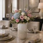 گلدان شیشه‌ای دکوراتیو رومیزی مدل کاترین سایز 30؛ ترکیبی از طراحی مدرن و ظرافت هنرمندانه اگر به دنبال یک گلدان خاص و متفاوت برای تکمیل دکوراسیون منزل یا محل کار خود هستید، گلدان شیشه‌ای دکوراتیو رومیزی مدل کاترین سایز 30 انتخابی ایده‌آل خواهد بود. این گلدان با طراحی استوانه‌ای کشیده، ترکیب دو نوع بافت متفاوت روی بدنه، رنگ مرواریدی درخشان و لبه طلایی براق، جلوه‌ای لوکس و مدرن به فضای شما می‌بخشد. گلدان شیشه‌ای دکوراتیو رومیزی مدل کاترین سایز 30 علاوه بر زیبایی ظاهری، با ارتفاع مناسب خود برای گل‌آرایی‌های شاخه‌ای نیز بسیار کاربردی است. طراحی منحصربه‌فرد این مدل باعث شده تا حتی بدون قرار گرفتن گل، به‌عنوان یک اکسسوری دکوراتیو مستقل نیز جلوه‌ای چشمگیر داشته باشد. طراحی گلدان شیشه‌ای دکوراتیو رومیزی مدل کاترین سایز 30 یکی از مهم‌ترین ویژگی‌های گلدان شیشه‌ای دکوراتیو رومیزی مدل کاترین سایز 30، طراحی متفاوت بدنه آن است. بخش پایینی گلدان با شیارهای عمودی منظم طراحی شده که حس نظم و ظرافت را به نمایش می‌گذارد، در حالی که قسمت بالایی با خطوط مارپیچی برجسته، جلوه‌ای پویا و مدرن ایجاد کرده است. ترکیب این دو نوع بافت در کنار رنگ مرواریدی براق، باعث می‌شود نور در زوایای مختلف به زیبایی روی سطح گلدان منعکس شود و درخشش خاصی به آن ببخشد. لبه طلایی صیقلی نیز هماهنگی زیبایی با بدنه ایجاد کرده و ظاهر لوکس این محصول را کامل می‌کند. ابعاد گلدان شیشه‌ای دکوراتیو رومیزی مدل کاترین سایز 30 گلدان شیشه‌ای دکوراتیو رومیزی مدل کاترین سایز 30 با ابعاد استاندارد و کاربردی طراحی شده است و برای استفاده در بخش‌های مختلف منزل یا محیط کار مناسب است. مشخصات این محصول عبارت‌اند از: ارتفاع: 30 سانتی‌متر قطر دهانه: 8 سانتی‌متر ارتفاع مناسب این گلدان باعث شده برای گل‌های شاخه‌ای بلند و چیدمان‌های دکوراتیو انتخابی ایده‌آل باشد. کاربرد گلدان شیشه‌ای دکوراتیو رومیزی مدل کاترین سایز 30 در گل‌آرایی گلدان شیشه‌ای دکوراتیو رومیزی مدل کاترین سایز 30 برای انواع گل‌آرایی طراحی شده و می‌تواند زیبایی گل‌ها را چندین برابر کند. این گلدان برای استفاده با موارد زیر مناسب است: گل‌های طبیعی گل‌های مصنوعی گل‌های خشک پامپاس اکالیپتوس شاخه‌های بلند تزئینی برگ‌های دکوراتیو گل‌های فصلی فرم استوانه‌ای و کشیده این مدل باعث می‌شود شاخه‌های گل به‌صورت منظم قرار گرفته و جلوه‌ای حرفه‌ای و زیبا ایجاد کنند. گلدان شیشه‌ای دکوراتیو رومیزی مدل کاترین سایز 30 مناسب چه دکوراسیونی است؟ به دلیل طراحی مدرن و رنگ خنثی، گلدان شیشه‌ای دکوراتیو رومیزی مدل کاترین سایز 30 با سبک‌های مختلف دکوراسیون هماهنگ می‌شود. این گلدان برای فضاهای زیر انتخابی مناسب است: دکوراسیون مدرن دکوراسیون مینیمال دکوراسیون نئوکلاسیک دکوراسیون کلاسیک سبک معاصر دکوراسیون لوکس همچنین رنگ مرواریدی این محصول به‌راحتی با رنگ‌های سفید، کرم، بژ، طوسی، طلایی، چوب طبیعی و سبز زیتونی هماهنگ شده و فضایی آرام، شیک و دلنشین ایجاد می‌کند. کیفیت ساخت گلدان شیشه‌ای دکوراتیو رومیزی مدل کاترین سایز 30 در ساخت گلدان شیشه‌ای دکوراتیو رومیزی مدل کاترین سایز 30 از شیشه باکیفیت استفاده شده است که علاوه بر شفافیت و درخشندگی، دوام مناسبی نیز دارد. پرداخت دقیق شیارهای عمودی، خطوط مارپیچی و لبه طلایی نشان‌دهنده کیفیت بالای ساخت این محصول است. سطح براق گلدان نیز باعث می‌شود در نور طبیعی و مصنوعی جلوه‌ای چشمگیر داشته باشد. چرا گلدان شیشه‌ای دکوراتیو رومیزی مدل کاترین سایز 30 را انتخاب کنیم؟ اگر به دنبال یک گلدان دکوراتیو خاص و باکیفیت هستید، این مدل مزایای فراوانی دارد: طراحی مدرن با دو نوع بافت متفاوت رنگ مرواریدی درخشان و چشم‌نواز لبه طلایی براق و لوکس مناسب برای گل‌های شاخه‌ای بلند ابعاد استاندارد و کاربردی مناسب برای گل طبیعی، مصنوعی و خشک هماهنگ با انواع سبک‌های دکوراسیون کیفیت ساخت بالا مناسب برای منزل، محل کار و هدیه راهنمای نگهداری از گلدان شیشه‌ای دکوراتیو رومیزی مدل کاترین سایز 30 برای حفظ زیبایی و دوام این گلدان بهتر است نکات زیر را رعایت کنید: با آب ولرم و شوینده ملایم شسته شود. از اسکاچ زبر یا مواد شوینده قوی استفاده نشود. پس از شست‌وشو با دستمال نرم و بدون پرز خشک شود. از وارد شدن ضربه مستقیم به بدنه جلوگیری گردد. برای حفظ درخشندگی لبه طلایی، از تماس طولانی‌مدت با مواد شیمیایی خودداری شود. خرید گلدان شیشه‌ای دکوراتیو رومیزی مدل کاترین سایز 30 اگر قصد خرید یک گلدان شیشه‌ای دکوراتیو رومیزی با طراحی متفاوت، کیفیت بالا و ظاهری لوکس را دارید، گلدان شیشه‌ای دکوراتیو رومیزی مدل کاترین سایز 30 یکی از بهترین گزینه‌ها برای شما خواهد بود. طراحی خاص با ترکیب شیارهای عمودی و خطوط مارپیچی، رنگ مرواریدی درخشان و لبه طلایی، این گلدان را به محصولی منحصربه‌فرد برای دکوراسیون منزل، محل کار و فضاهای تجاری تبدیل کرده است. این مدل علاوه بر کاربرد در گل‌آرایی، به‌تنهایی نیز یک اکسسوری دکوراتیو ارزشمند محسوب می‌شود و می‌تواند جلوه‌ای مدرن و لوکس به فضای شما ببخشد. اگر به دنبال محصولی زیبا، باکیفیت و ماندگار هستید، گلدان شیشه‌ای دکوراتیو رومیزی مدل کاترین سایز 30 انتخابی هوشمندانه برای تکمیل دکوراسیون شما خواهد بود.