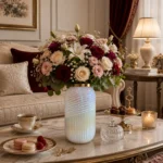گلدان شیشه‌ای دکوراتیو رومیزی مدل کاترین سایز 30؛ ترکیبی از طراحی مدرن و ظرافت هنرمندانه اگر به دنبال یک گلدان خاص و متفاوت برای تکمیل دکوراسیون منزل یا محل کار خود هستید، گلدان شیشه‌ای دکوراتیو رومیزی مدل کاترین سایز 30 انتخابی ایده‌آل خواهد بود. این گلدان با طراحی استوانه‌ای کشیده، ترکیب دو نوع بافت متفاوت روی بدنه، رنگ مرواریدی درخشان و لبه طلایی براق، جلوه‌ای لوکس و مدرن به فضای شما می‌بخشد. گلدان شیشه‌ای دکوراتیو رومیزی مدل کاترین سایز 30 علاوه بر زیبایی ظاهری، با ارتفاع مناسب خود برای گل‌آرایی‌های شاخه‌ای نیز بسیار کاربردی است. طراحی منحصربه‌فرد این مدل باعث شده تا حتی بدون قرار گرفتن گل، به‌عنوان یک اکسسوری دکوراتیو مستقل نیز جلوه‌ای چشمگیر داشته باشد. طراحی گلدان شیشه‌ای دکوراتیو رومیزی مدل کاترین سایز 30 یکی از مهم‌ترین ویژگی‌های گلدان شیشه‌ای دکوراتیو رومیزی مدل کاترین سایز 30، طراحی متفاوت بدنه آن است. بخش پایینی گلدان با شیارهای عمودی منظم طراحی شده که حس نظم و ظرافت را به نمایش می‌گذارد، در حالی که قسمت بالایی با خطوط مارپیچی برجسته، جلوه‌ای پویا و مدرن ایجاد کرده است. ترکیب این دو نوع بافت در کنار رنگ مرواریدی براق، باعث می‌شود نور در زوایای مختلف به زیبایی روی سطح گلدان منعکس شود و درخشش خاصی به آن ببخشد. لبه طلایی صیقلی نیز هماهنگی زیبایی با بدنه ایجاد کرده و ظاهر لوکس این محصول را کامل می‌کند. ابعاد گلدان شیشه‌ای دکوراتیو رومیزی مدل کاترین سایز 30 گلدان شیشه‌ای دکوراتیو رومیزی مدل کاترین سایز 30 با ابعاد استاندارد و کاربردی طراحی شده است و برای استفاده در بخش‌های مختلف منزل یا محیط کار مناسب است. مشخصات این محصول عبارت‌اند از: ارتفاع: 30 سانتی‌متر قطر دهانه: 8 سانتی‌متر ارتفاع مناسب این گلدان باعث شده برای گل‌های شاخه‌ای بلند و چیدمان‌های دکوراتیو انتخابی ایده‌آل باشد. کاربرد گلدان شیشه‌ای دکوراتیو رومیزی مدل کاترین سایز 30 در گل‌آرایی گلدان شیشه‌ای دکوراتیو رومیزی مدل کاترین سایز 30 برای انواع گل‌آرایی طراحی شده و می‌تواند زیبایی گل‌ها را چندین برابر کند. این گلدان برای استفاده با موارد زیر مناسب است: گل‌های طبیعی گل‌های مصنوعی گل‌های خشک پامپاس اکالیپتوس شاخه‌های بلند تزئینی برگ‌های دکوراتیو گل‌های فصلی فرم استوانه‌ای و کشیده این مدل باعث می‌شود شاخه‌های گل به‌صورت منظم قرار گرفته و جلوه‌ای حرفه‌ای و زیبا ایجاد کنند. گلدان شیشه‌ای دکوراتیو رومیزی مدل کاترین سایز 30 مناسب چه دکوراسیونی است؟ به دلیل طراحی مدرن و رنگ خنثی، گلدان شیشه‌ای دکوراتیو رومیزی مدل کاترین سایز 30 با سبک‌های مختلف دکوراسیون هماهنگ می‌شود. این گلدان برای فضاهای زیر انتخابی مناسب است: دکوراسیون مدرن دکوراسیون مینیمال دکوراسیون نئوکلاسیک دکوراسیون کلاسیک سبک معاصر دکوراسیون لوکس همچنین رنگ مرواریدی این محصول به‌راحتی با رنگ‌های سفید، کرم، بژ، طوسی، طلایی، چوب طبیعی و سبز زیتونی هماهنگ شده و فضایی آرام، شیک و دلنشین ایجاد می‌کند. کیفیت ساخت گلدان شیشه‌ای دکوراتیو رومیزی مدل کاترین سایز 30 در ساخت گلدان شیشه‌ای دکوراتیو رومیزی مدل کاترین سایز 30 از شیشه باکیفیت استفاده شده است که علاوه بر شفافیت و درخشندگی، دوام مناسبی نیز دارد. پرداخت دقیق شیارهای عمودی، خطوط مارپیچی و لبه طلایی نشان‌دهنده کیفیت بالای ساخت این محصول است. سطح براق گلدان نیز باعث می‌شود در نور طبیعی و مصنوعی جلوه‌ای چشمگیر داشته باشد. چرا گلدان شیشه‌ای دکوراتیو رومیزی مدل کاترین سایز 30 را انتخاب کنیم؟ اگر به دنبال یک گلدان دکوراتیو خاص و باکیفیت هستید، این مدل مزایای فراوانی دارد: طراحی مدرن با دو نوع بافت متفاوت رنگ مرواریدی درخشان و چشم‌نواز لبه طلایی براق و لوکس مناسب برای گل‌های شاخه‌ای بلند ابعاد استاندارد و کاربردی مناسب برای گل طبیعی، مصنوعی و خشک هماهنگ با انواع سبک‌های دکوراسیون کیفیت ساخت بالا مناسب برای منزل، محل کار و هدیه راهنمای نگهداری از گلدان شیشه‌ای دکوراتیو رومیزی مدل کاترین سایز 30 برای حفظ زیبایی و دوام این گلدان بهتر است نکات زیر را رعایت کنید: با آب ولرم و شوینده ملایم شسته شود. از اسکاچ زبر یا مواد شوینده قوی استفاده نشود. پس از شست‌وشو با دستمال نرم و بدون پرز خشک شود. از وارد شدن ضربه مستقیم به بدنه جلوگیری گردد. برای حفظ درخشندگی لبه طلایی، از تماس طولانی‌مدت با مواد شیمیایی خودداری شود. خرید گلدان شیشه‌ای دکوراتیو رومیزی مدل کاترین سایز 30 اگر قصد خرید یک گلدان شیشه‌ای دکوراتیو رومیزی با طراحی متفاوت، کیفیت بالا و ظاهری لوکس را دارید، گلدان شیشه‌ای دکوراتیو رومیزی مدل کاترین سایز 30 یکی از بهترین گزینه‌ها برای شما خواهد بود. طراحی خاص با ترکیب شیارهای عمودی و خطوط مارپیچی، رنگ مرواریدی درخشان و لبه طلایی، این گلدان را به محصولی منحصربه‌فرد برای دکوراسیون منزل، محل کار و فضاهای تجاری تبدیل کرده است. این مدل علاوه بر کاربرد در گل‌آرایی، به‌تنهایی نیز یک اکسسوری دکوراتیو ارزشمند محسوب می‌شود و می‌تواند جلوه‌ای مدرن و لوکس به فضای شما ببخشد. اگر به دنبال محصولی زیبا، باکیفیت و ماندگار هستید، گلدان شیشه‌ای دکوراتیو رومیزی مدل کاترین سایز 30 انتخابی هوشمندانه برای تکمیل دکوراسیون شما خواهد بود.